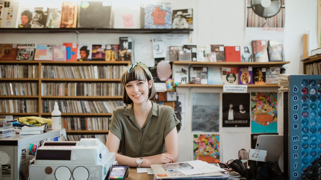 smiling woman behind the counter of a record store